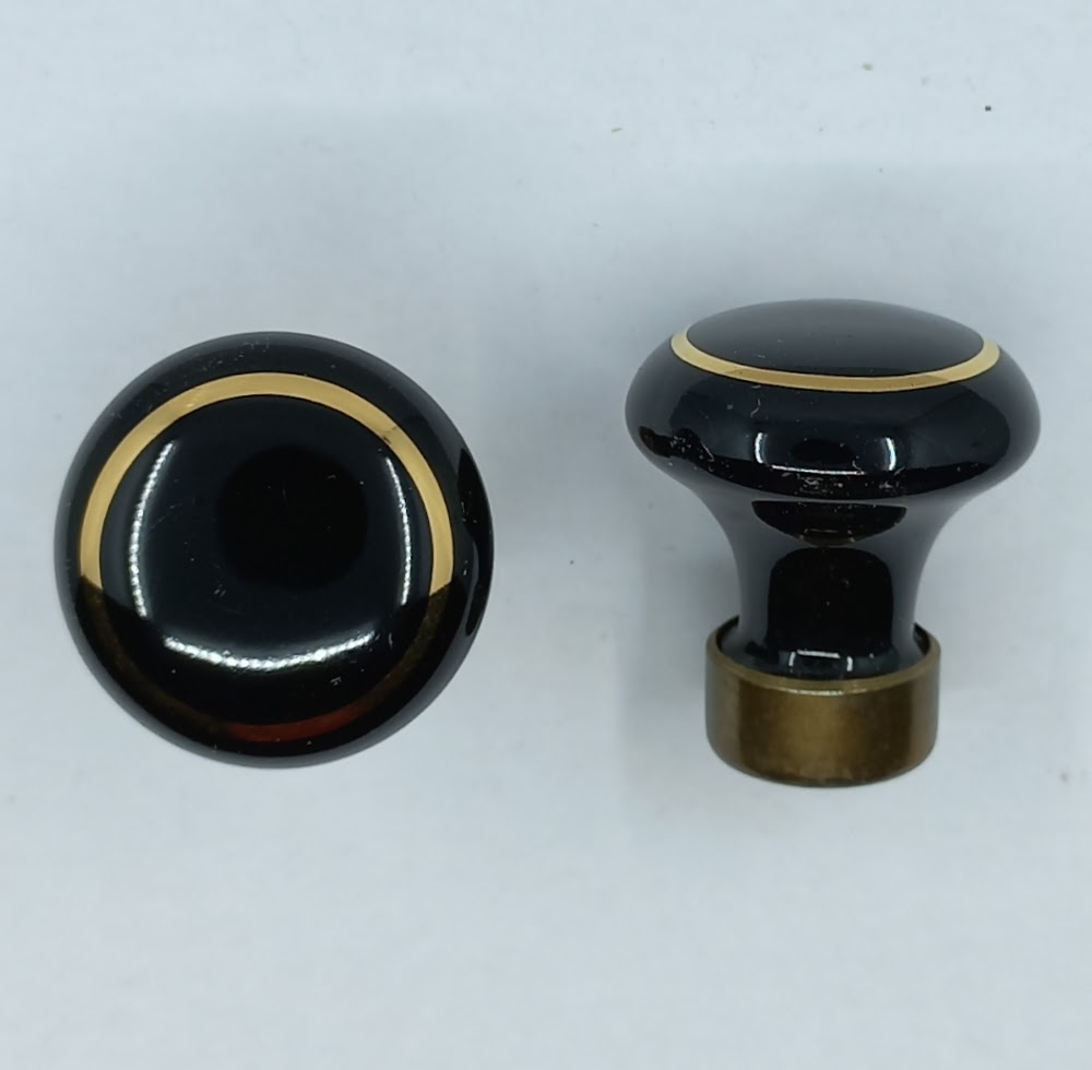 Bouton porcelaine 55.611. noir avec filet or, diam. 25-30-35-50mm, avec base laiton M4. Pour le montage, tenir le bouton par la base et fixer avec la vis.